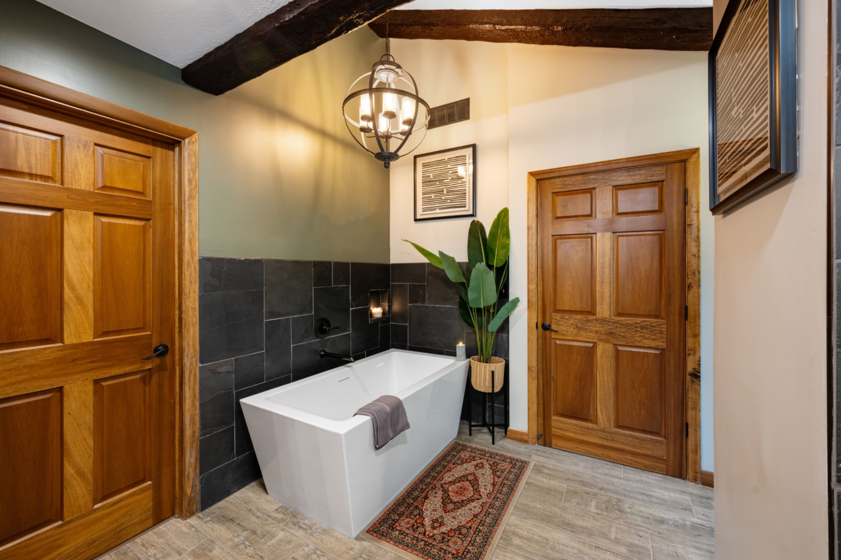 Finished freestanding soaking tub with slate tile surround and wood beam ceiling