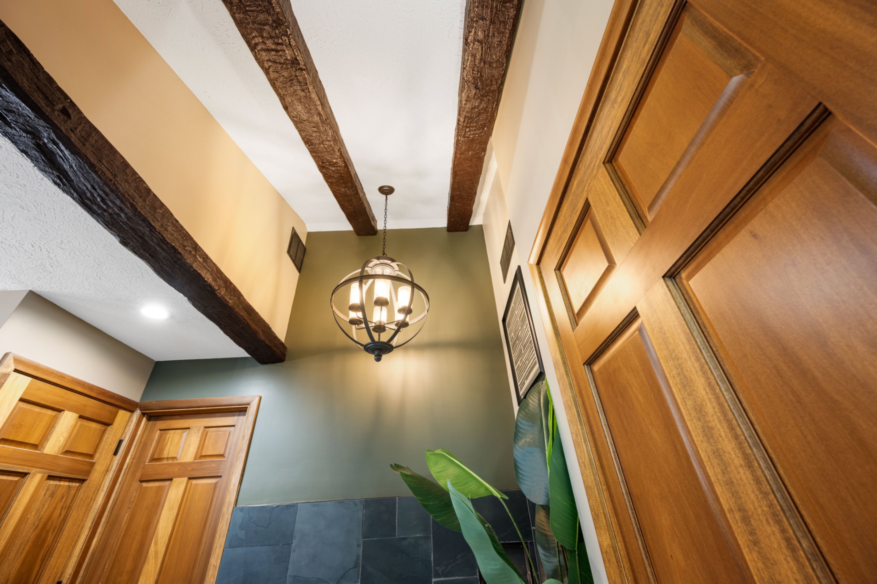 Finished bathroom ceiling with custom faux wood beams and globe light fixture