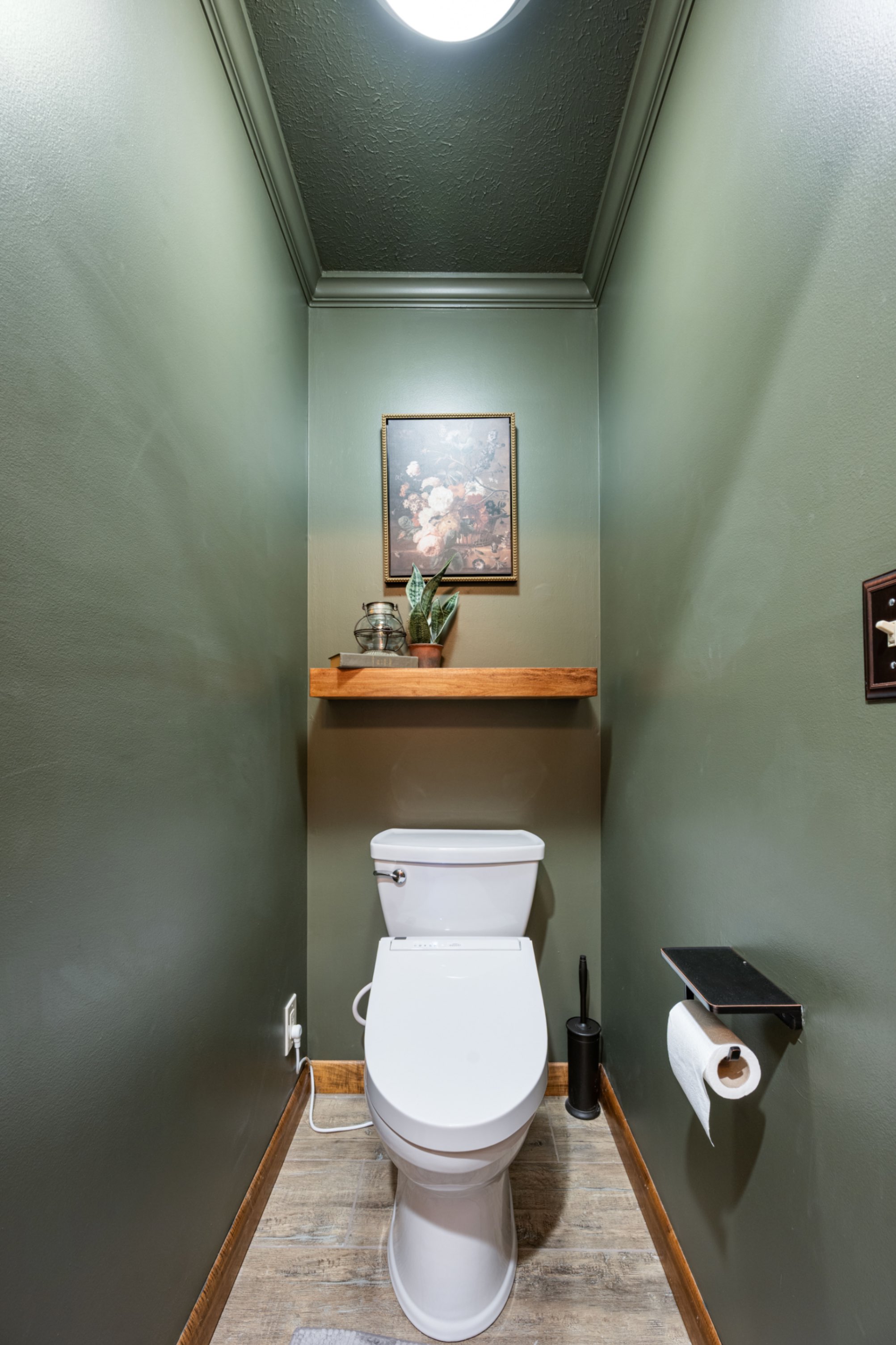 Private water closet with sage green walls, custom floating shelf, and heated floor