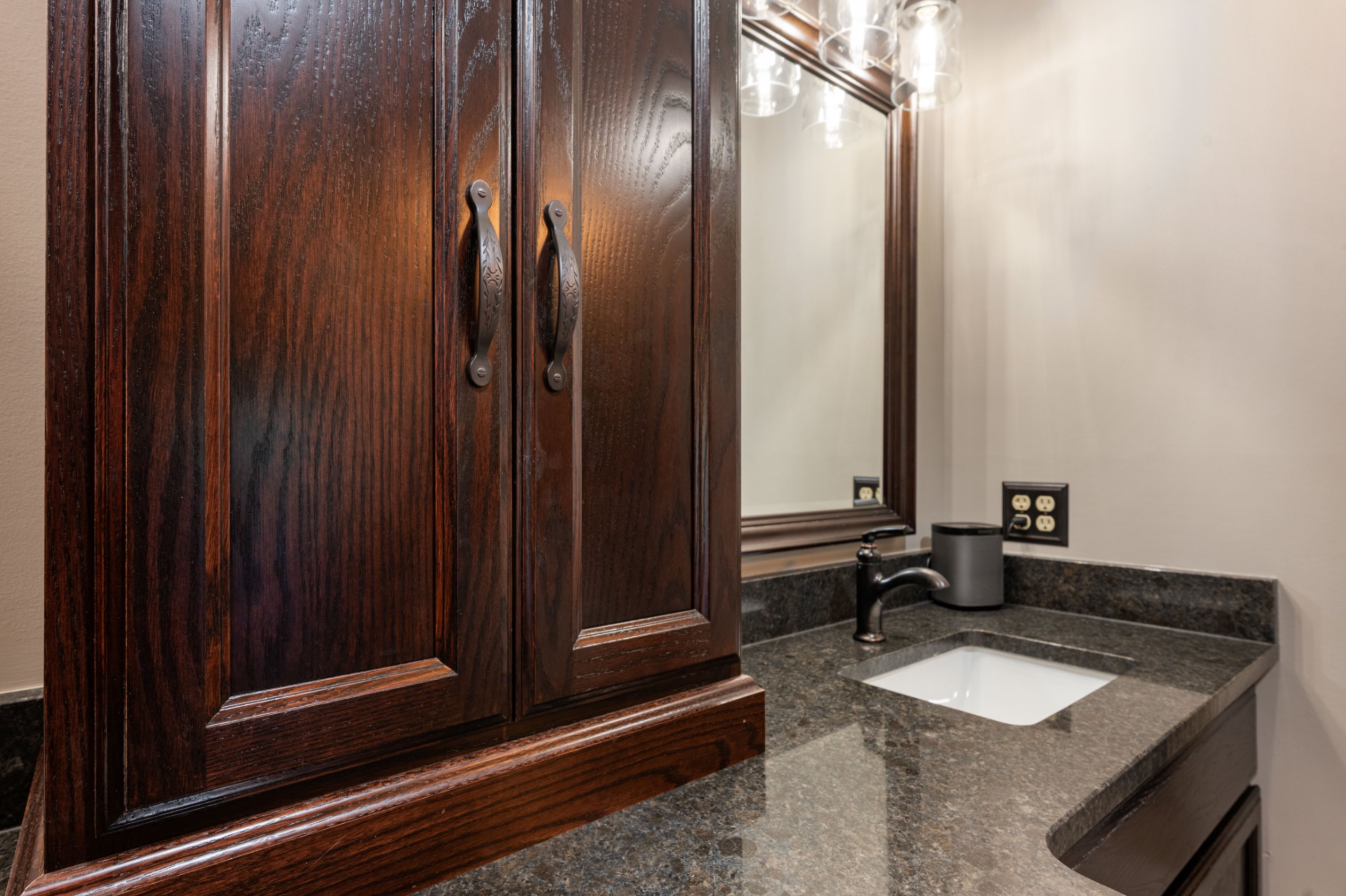 Custom storage tower cabinet with dark hardware and granite top